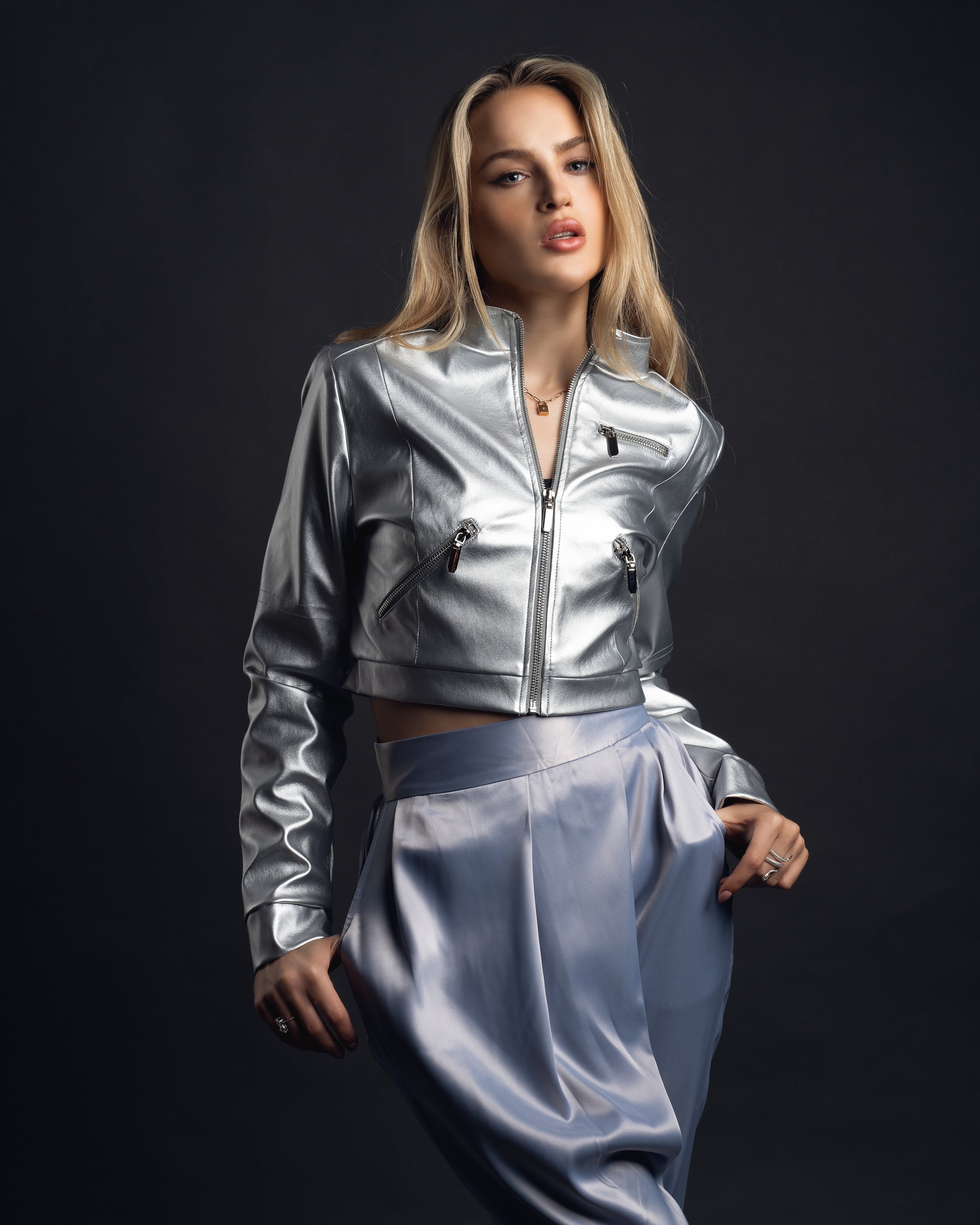 Model featured wearing our metallic cropped jacket that features zipper detailing, topstitching, pockets, a collar, shoulder detailing, and lined with silky silver material. 